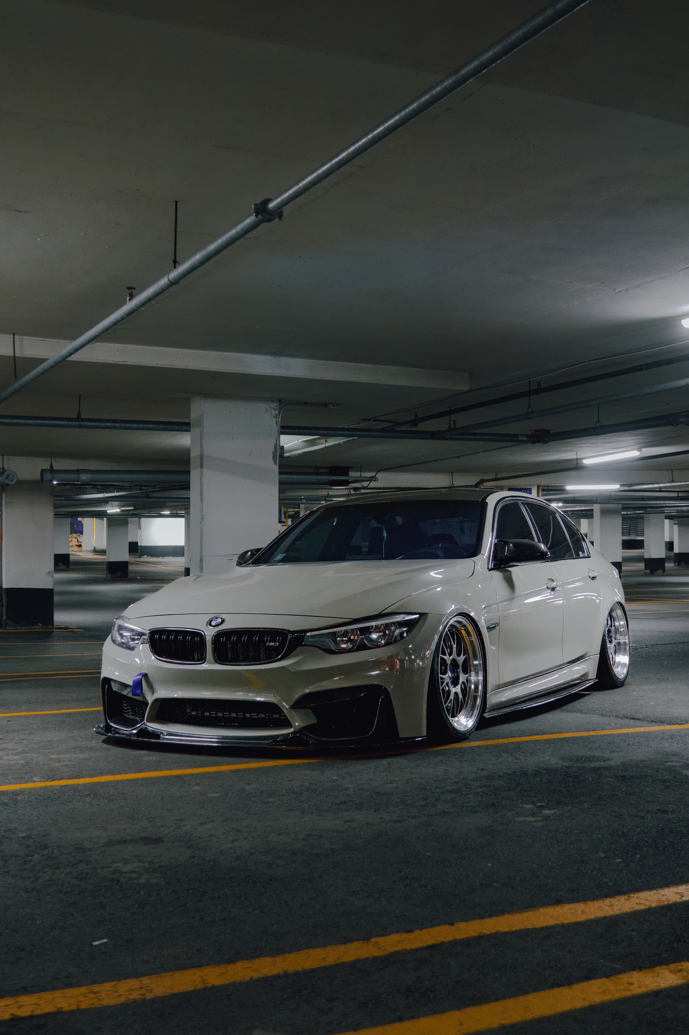 White BMW M3 parked in a concrete parking garage